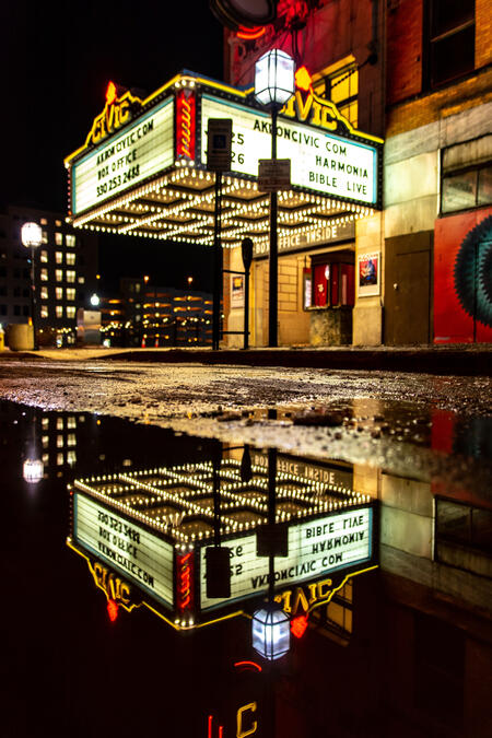 The Akron Civic Theatre at night with a reflection of the marquee in a puddle.