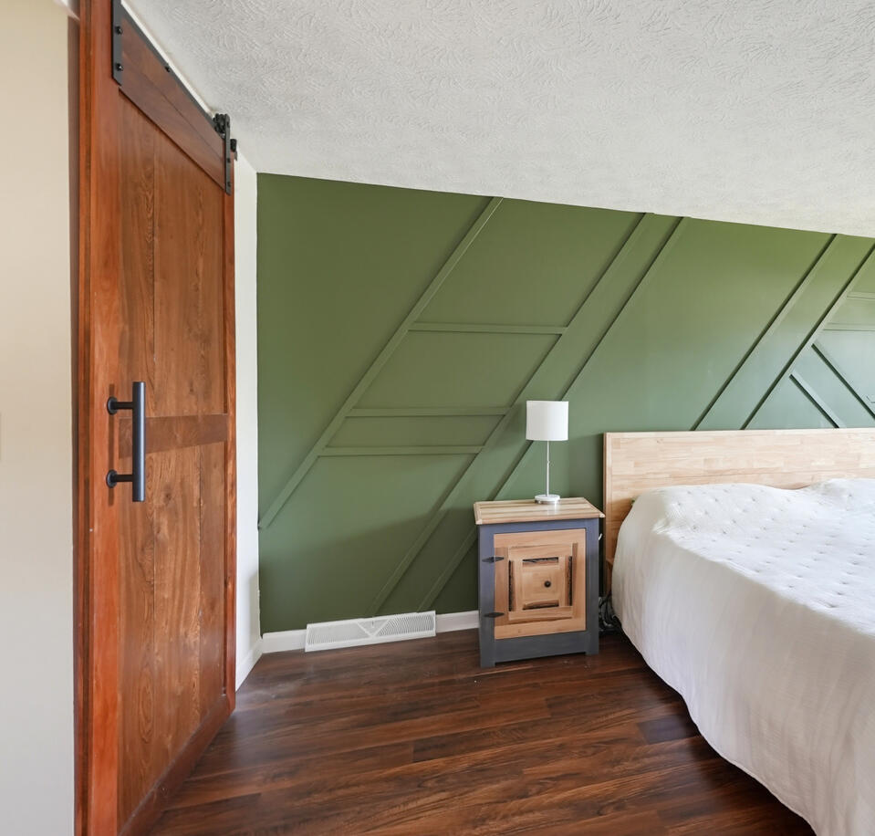 Bedroom with a trendy green feature wall in a Northeast, Ohio home represented by Limitless Real Estate Group.